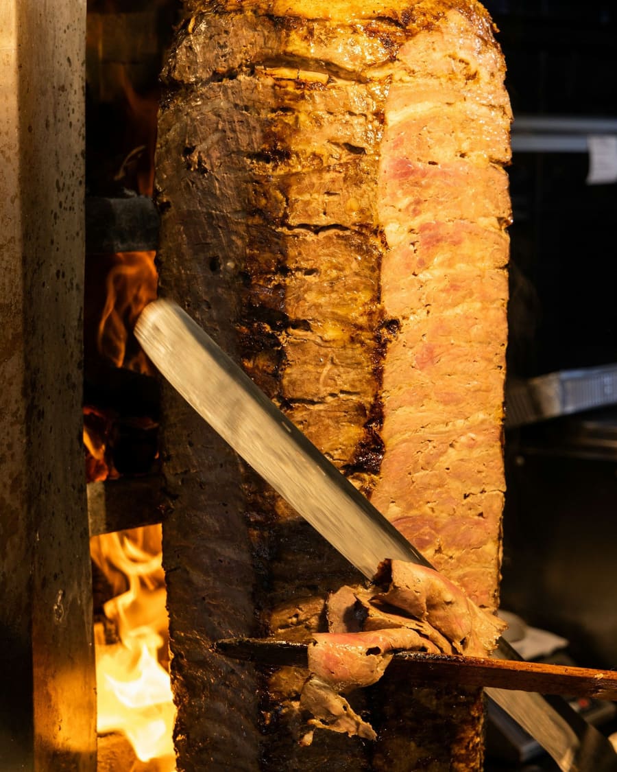 Dönerspieß am Grill, das Fleisch wird mit dem Messer abgeschnitten